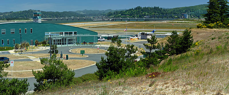 OR: South Coast Region, Coos County, Coos Bay Area, City of North Bend, North Bend Regional Airport, Panoramic view of the airport terminal and runways, with McCollough Bridge (US 101) in the background [Ask for #274.184.]