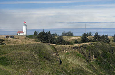 OR: South Coast Region, Curry County, North Coast, Cape Blanco Area, Cape Blanco State Park, View of the Cape Blanco Lighthouse atop grassy cliffs as fog rolls in. [Ask for #274.683.]