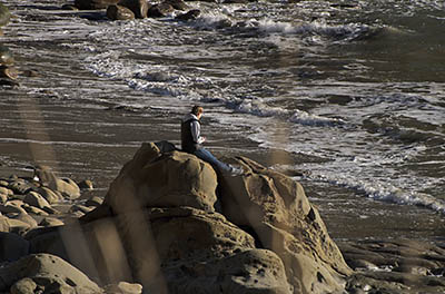 OR: Coos County, Coos Bay Area, Cape Arago Parks, South Cove, A young woman sits upon a sea rock [Ask for #276.377.]