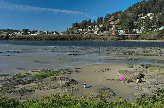 OR: North Coast Region, Lincoln County, Pacific Coast, Yachats Area, Yachats Proper, A family enjoys a low tide beach along the inlet of the Yachats River, with the town visible in the background [Ask for #276.545.]